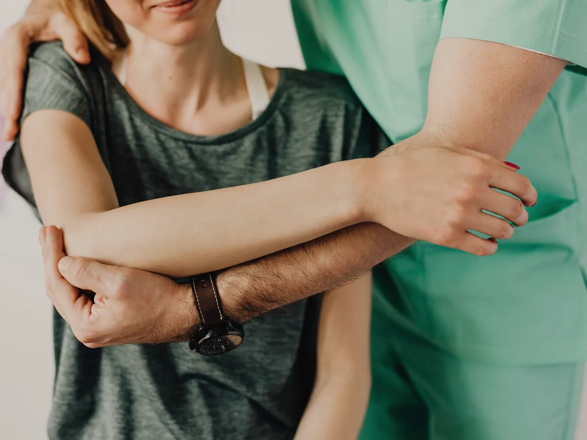 A physiotherapist guiding a patient's arm through a shoulder mobilisation.