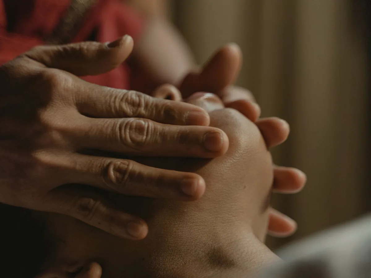 A physiotherapist's hands treating a patient's jaw.