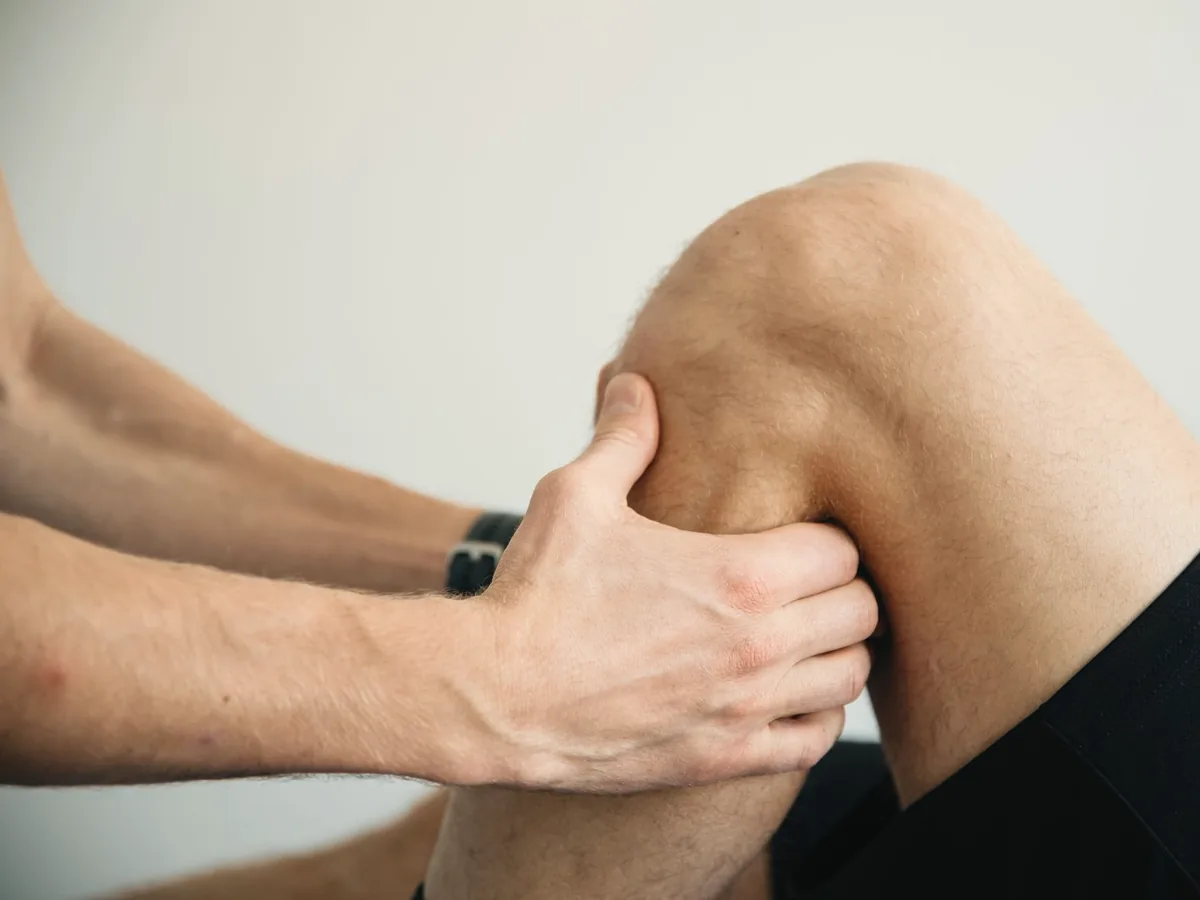 A physiotherapist's hands examining a patient's knee.