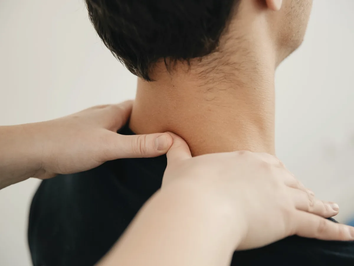 A physiotherapist's hands working on a patient's neck and upper back.